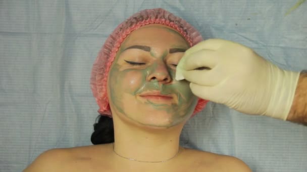 Kosmetologene Tar Seg Hanskene Fjerner Muddermasken Fra Kvinnens Ansikt Med – stockvideo