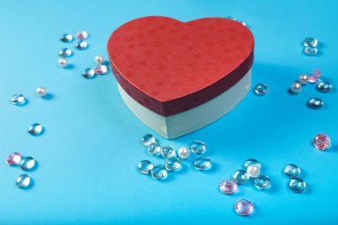 İle mavi bir arka plan üzerinde beyaz boncuk çerçevesinde bir kalp şeklinde Sevgililer günü için bir hediye kutusu.