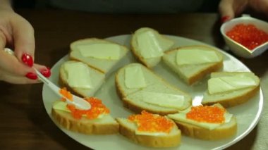 Bir kadın Iornitsa bir kaşık kırmızı havyar alır ve bir kanepe üzerinde tereyağı tereyağı ile yayılır