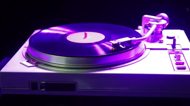The player plays music on a vinyl record in the light of disco — Stock Video