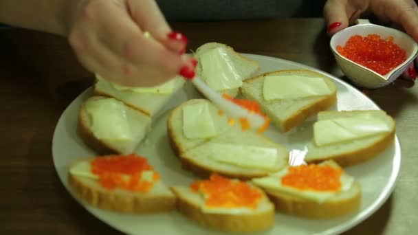 Uma mulher toma caviar vermelho de uma colher de Iornitsa e espalha manteiga em um canapé com manteiga — Vídeo de Stock