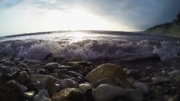 Le bord de mer rocheux sur lequel les vagues roulent au coucher du soleil — Video