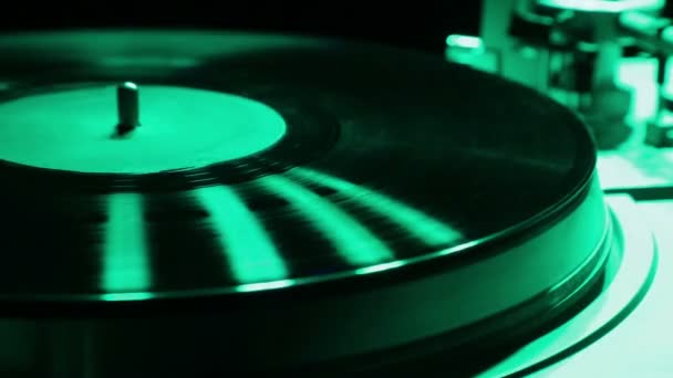 Female hand sets a turntable needle on a vinyl record in color light — Stock Video