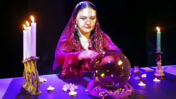 Gypsy in een rode jurk in een sjaal leest de toekomst in een spiegel-bal — Stockvideo