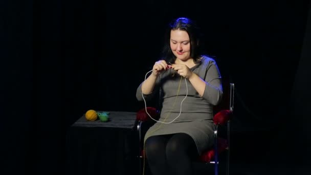 Young woman on a black background knits on circular needles — Stock Video