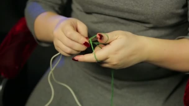Les mains des femmes sur un fond noir cadrans sur les rayons d'une boucle de fil vert 