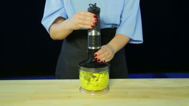 Eine Frau hackt Kiwi und Mango in einem Mixer — Stockvideo