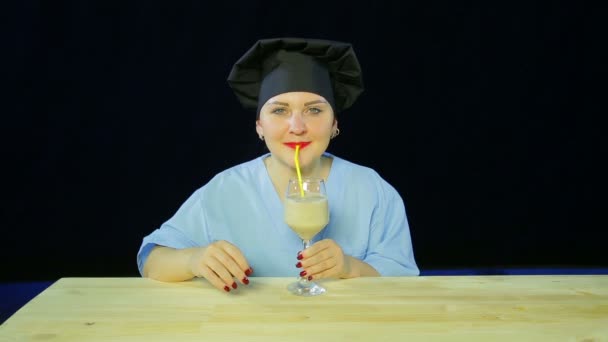 Kvinna kock på en svart bakgrund smakar fruktsmoothie och visar skylten Ok — Stockvideo