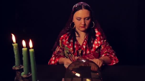 Циганський капелюх за столом свічками поширює листівки з удачею — стокове відео