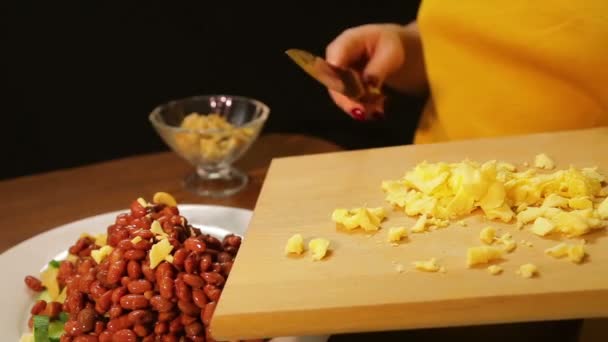 Een vrouw is met behulp van een mes Strooi geraspte kaas in een plaat van salade — Stockvideo