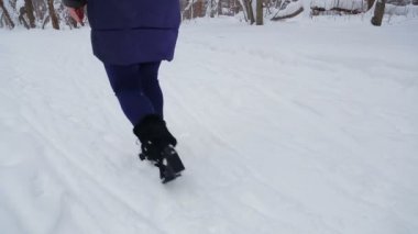 İçinde genç bir kadın gülümsüyor kukuIeta kar yağışı kış Park'ta size yürür. Genel planı.