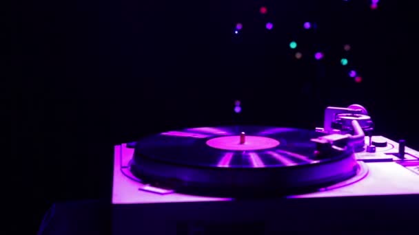De speler speelt muziek op een vinyl record in het licht van de disco — Stockvideo
