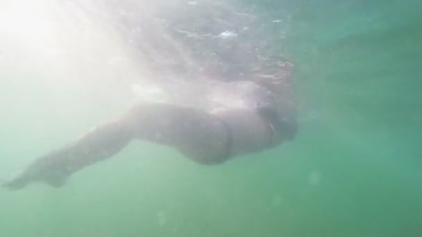 Silueta de una mujer flotante bajo el agua en el agua de mar en el sol — Vídeos de Stock