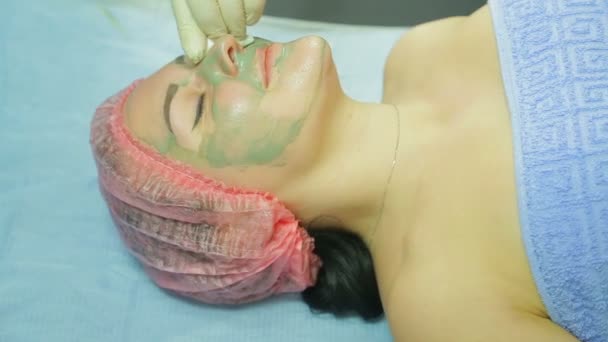 A female cosmetologist in gloves applies a treatment mask to a man s face with a brush — Stock Video