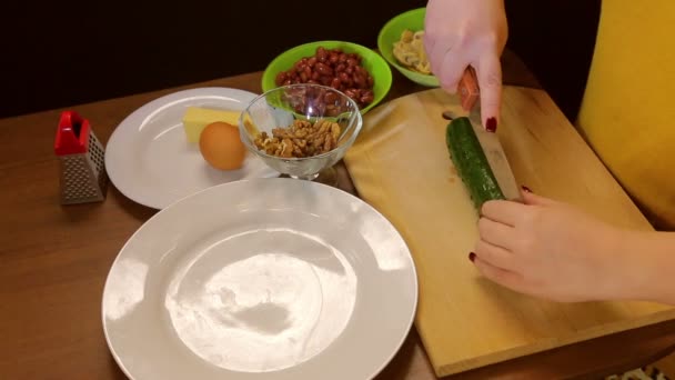Жіночі руки вирізають свіжий огірок на дерев'яній дошці — стокове відео