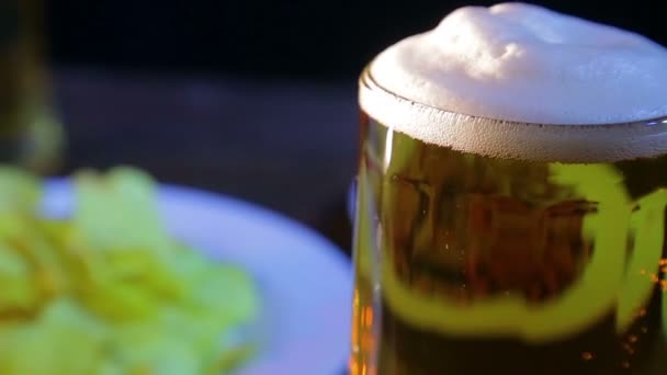 Tasse en verre avec de la bière légère mousseuse sur un fond noir . — Video