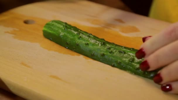 Vrouw mes plakjes verse komkommer op een houten bord — Stockvideo