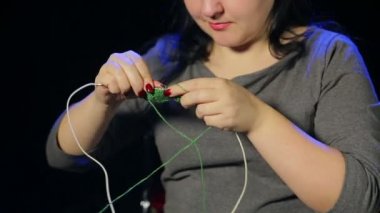 Siyah bir arka planda genç kadın yeşil iplik iğneler üzerinde örme