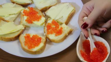 Bir kadın bir kaşık tereyağı ile kanepeler, kırmızı havyar smear