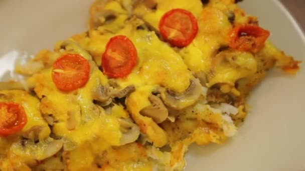 Peixe cozido no forno abaixo do queijo com cogumelos e tomates de cereja em uma chapa branca . — Vídeo de Stock