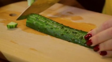Kadın taze yeşil salatalık ahşap tahta keser. Zaman sukut