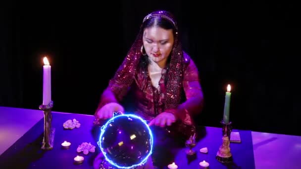 En el salón mágico, el gitano lee el futuro en una bola mágica rodeada de deslumbramiento . — Vídeo de stock