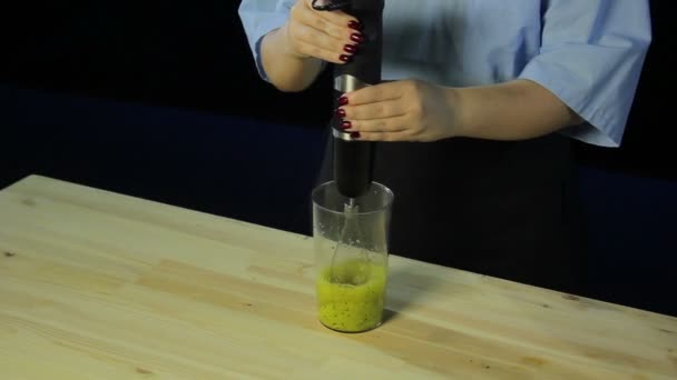 Femme cuisinier sur un fond noir bat kiwi et mangue dans un mélangeur — Video