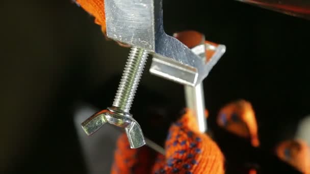 Tändaren i arbetshandskar unscrews klämman skruven — Stockvideo