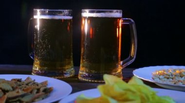 Siyah bir arka plan karşı ahşap bir masa üzerinde köpük light bira ile kupalar