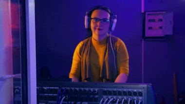 Teknik bir odada kulaklıklarla kadın Dj karıştırma konsolu bir disko ışığında bir diskoda yürütmektedir.
