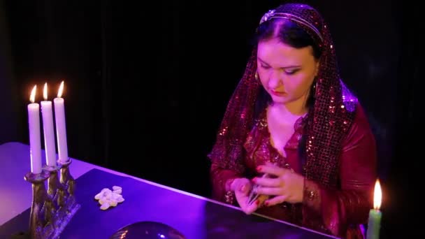 Eine junge Zigeunerin bei Kerzenschein im Rauch legt Karten auf den Tisch — Stockvideo