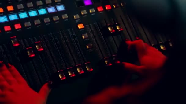 Kvinnliga händer bakom mixerbordet blandar spår för disco i färg belysning — Stockvideo