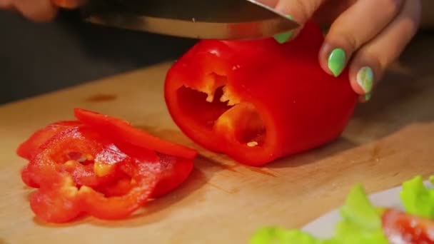 La mano femenina corta el pimiento rojo en una tabla de madera con un cuchillo. Vueltas de tiempo — Vídeo de stock