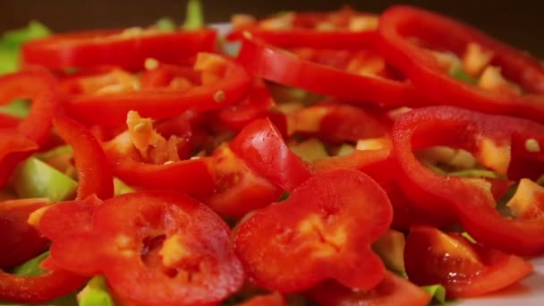 Vrouwelijke hand zet avocado segmenten in een bord met salade en peper — Stockvideo