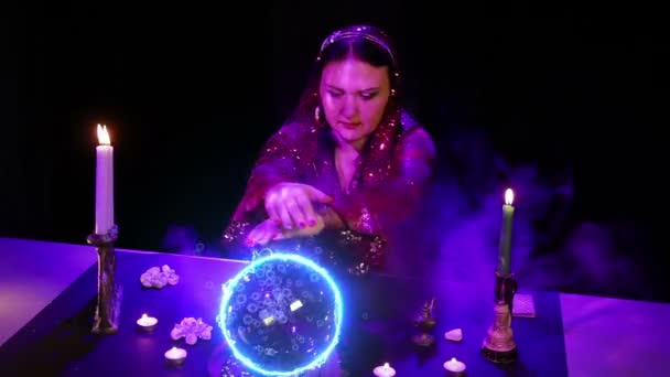 桌子上的一个吉普赛人正在用一个发出电火花和气泡的水晶球进行魔术 平均计划 — 图库视频影像