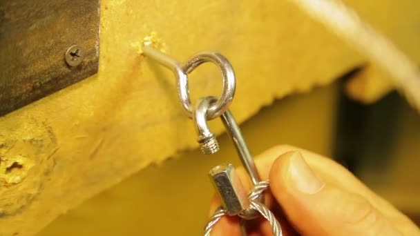 De man maakt vast aan de montage ring in de muur een veiligheidskabel voor theatrale schijnwerpers — Stockvideo