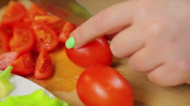 El kiraz domates bir ahşap tahta üzerinde bir bıçakla keser.