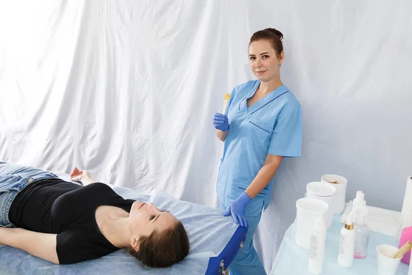 Una doctora esteticista está al lado de una paciente acostada en un massa — Foto de Stock