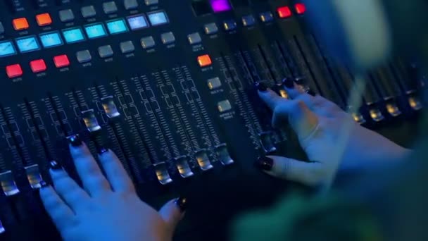 Vrouwelijke handen achter de mengtafel mixen tracks voor disco in kleur verlichting — Stockvideo