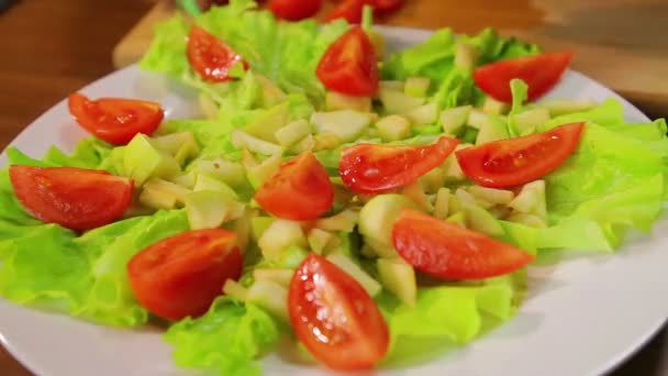 Main féminine met des tranches de tomate cerise dans une assiette avec salade . — Video