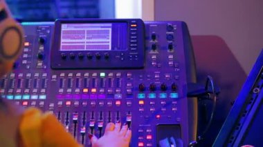 Kadın Dj kulaklık arkasında renkli aydınlatma çalışan bir karıştırma konsolu