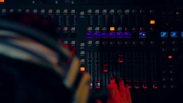 Dames handen op een mengpaneel mengen tracks voor disco in kleur verlichting — Stockvideo
