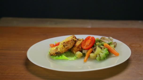 Une main de femme décore un plat de dinde avec des légumes, des tranches de tomate rouge et de sauce soja dans un bol à sauce . — Video