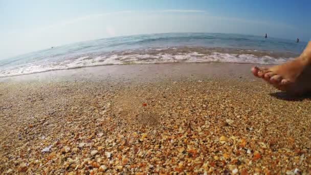 Piernas curtidas hembra caminando a lo largo de la orilla del mar dejando marcas en la arena — Vídeos de Stock