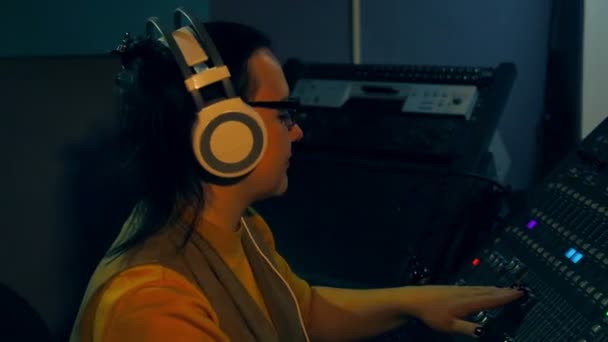 Femme DJ en casque et lunettes mixe des pistes pour disco sur une console de mixage — Video