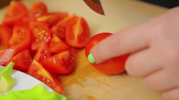 Kvinnlig hand skär en körsbärstomat med en kniv på en träskiva. — Stockvideo