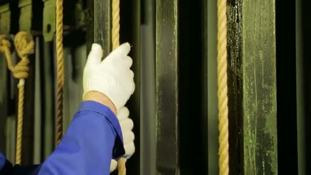 De handen van de mannelijke werknemer in de scene in handschoenen lift het theater gordijn met een kabel en bevestig het. — Stockvideo