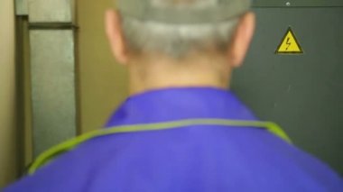 Bir elektrikçi mühendisi bir şalter ile bir elektrik anahtarı açar