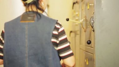 Bir kadın elektrik mühendisi bir elektrik paneli açar ve elektrik okumaları kaydeder