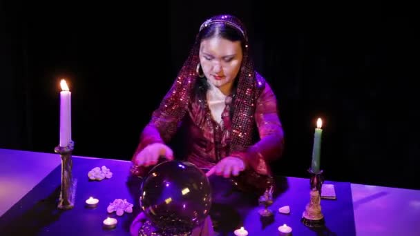 I den magiska salongen läser gypsy framtiden i en magisk boll omgiven av bländning. — Stockvideo